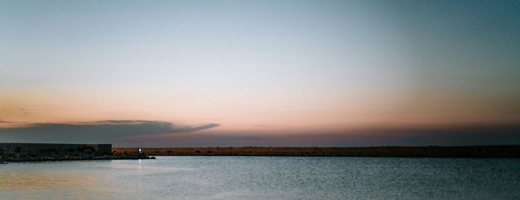 Calm water and a distant breakwater at dusk