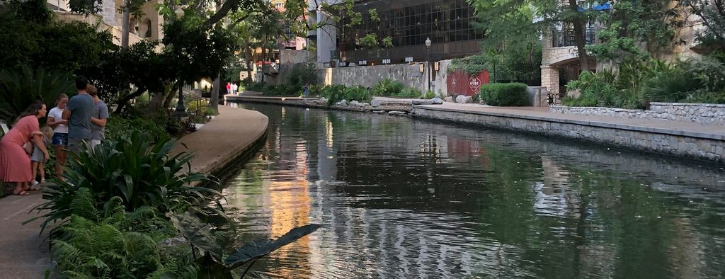 The San Antonio River Walk with trees and buildings reflected in the water